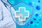 Immunologist and shield with cross as symbol of virus protection on light blue background, closeup