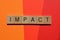 Impact, word in 3d wood letter blocks on red