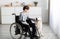 Impaired teenager in wheelchair stroking his cute golden retriever at home. Domestic animals therapy concept