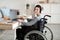 Impaired teenager in wheelchair studying online with laptop, using headphones for remote communication at home, mockup