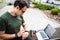 An important meeting. Stylish man sitting on bench with laptop and looking at watches