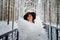 An imposing lady in a hat and with angel wings with white feathers in the forest in winter with snow covered trees. A