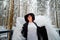 An imposing lady in a hat and with angel wings with white feathers in the forest in winter with snow covered trees. A