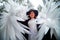 An imposing lady in a hat and with angel wings with white feathers in the forest in winter with snow covered trees. A