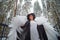 An imposing lady in a hat and with angel wings with white feathers in the forest in winter with snow covered trees. A