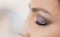 Imposition of artificial eyelashes. Eyelash extensions in a beauty salon. Attaching the lashes with tweezers to the eye.