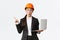 Impressed asian female entrepreneur at factory wearing safety helmet and business suit, pointing finger left and holding