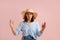 Impressed brunette makes big sign with both hands, shapes quite huge object, has eyes wide open, wears straw hat