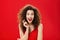 Impressed and excited feminine adult woman with curly hair in red lipstic and elegant evening dress gasping and smiling