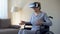 Impressed grandmother in wheelchair wearing goggles, playing VR game, device
