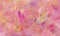Impressionistic pink background with purple yellow and red paint brush strokes and spots with crinkled rough glass texture