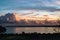 impressive billowing cumulus clouds at dusk along the horizon and reflecting in the sea.