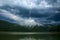 Impressive landscape of green coniferous mountains above lake against the background of stormy gray clouds, rainy weather, Ukraine