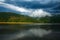 Impressive landscape of green coniferous mountains above lake against the background of stormy gray clouds, rainy weather, Ukraine