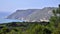 Impressive rocky cliffs covered with greenery on Atlantic Ocean coast in Portugal under blue sky