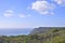 Impressive rocky cliffs covered with greenery on Atlantic Ocean coast in Portugal under blue sky