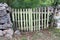 Improvised backyard door made from dilapidated wooden pallet mounted between traditional stone wall with dense branches and garden