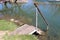 Improvised homemade wooden steps with metal frame mounted on river bank surrounded with uncut grass and local river