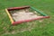 Improvised vintage retro colorful wooden sandbox made from four wooden logs filled with fine sand in apartment building backyard