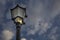 An incandescent bulb with a broken glass glowing in an antique street lamp post.The medieval european lamp post is made of cast st