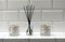 Incense holder and candle holders against white bathroom tiles on shelf