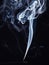 Incense stick smouldering with white aromatic smoke, isolated on black background. Abstract smoke, close up view. Smoke