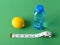 Inch measuring tape, ripe lemon and bottle of pure drinking water on a green background. Concept of healthy eating, diet, weight