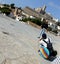 Inclined perspective of a photographer is bending over and a woman model with the historic citadel of Ibiza city