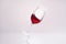 inclined wineglass with splashing red wine on reflective surface