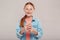 Inclusive Beauty. Girl with freckles in denim jacket standing isolated on grey with smartphone looking camera excited