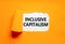 Inclusive capitalism symbol. Concept words Inclusive capitalism on beautiful white paper. Beautiful orange paper background.