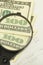 Income calculation concept. Magnifier increases denomination of one hundred dollars on numbers background