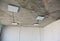 Incomplete room with ceiling square lightning loft design lamps and electric wiring installed on the ceiling without plastering