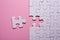 Incomplete white jigsaw puzzle pieces on pink background