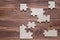 Incomplete wooden puzzles on brown wooden desk, top view, flat lay