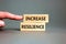 Increase resilience symbol. Concept word Increase resilience typed on wooden blocks. Beautiful grey table grey background.