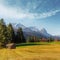 Incredible Bavarian Alps. View on Fairy Alpine valley with Tipical wooden huts, with Zugspitze mountain range at sunset. colorful