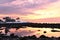 Incredible colorful sunrise on the shores of the Atlantic Ocean. Stony algae coastline and a lonely house among the firs in the di