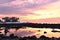 Incredible colorful sunrise on the shores of the Atlantic Ocean. Stony algae coastline and a lonely house among the firs in the di