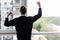 Incredible joy of win businessman with raised hands near office window