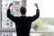 Incredible joy of win businessman with raised hands near office window