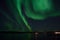 Incredible strong aurora borealis over fjord and snowy mountain