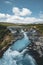 Incredible view of Bruarfoss Waterfall. The `Iceland s Bluest Waterfall.` Blue water flows over stones. Midnight sun of