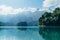 Incredible view of Cheow Lan lake with rainforest jungle on the banks with sun rays shining through white clouds. Surat Thani