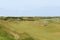 An incredible view of a classic links golf hole with pot bunkers in Scotland with the ocean in nearby