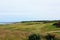 An incredible view of a classic links golf hole with pot bunkers in Scotland with the ocean in nearby