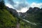 An incredible view of a majestic Shdugra waterfall in the distance, high in the Caucasus Mountains, rocky, a rushing stream. Green