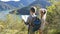 Independent little children scouts with tourist backpacks stand on the shore of a mountain lake in the Alps and pave the way for a