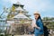 Independent travel in japan lifestyle concept. woman traveler holding guidebook visiting osaka castle alone carrying backpack and