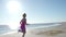 Independent young woman athlete running on beach exercising female runner sprinting training in sunny seaside background